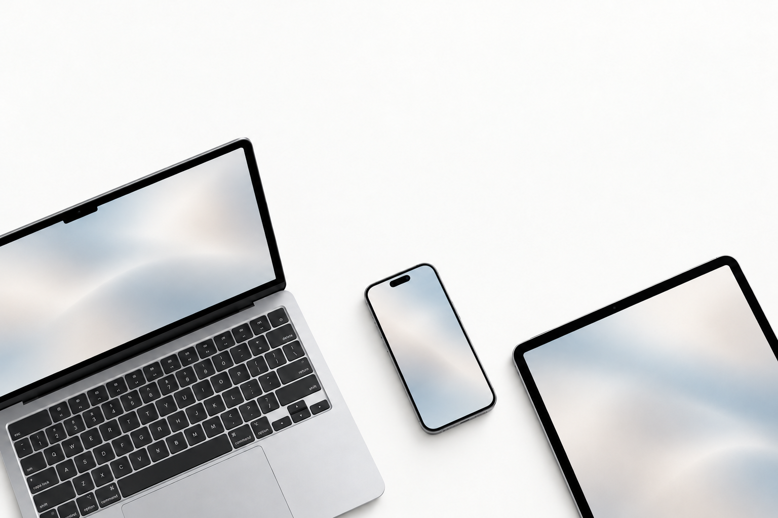 A Mac laptop, phone and iPad with soft fog-gray and warm stone gradient wallpapers, arranged on a clean white surface